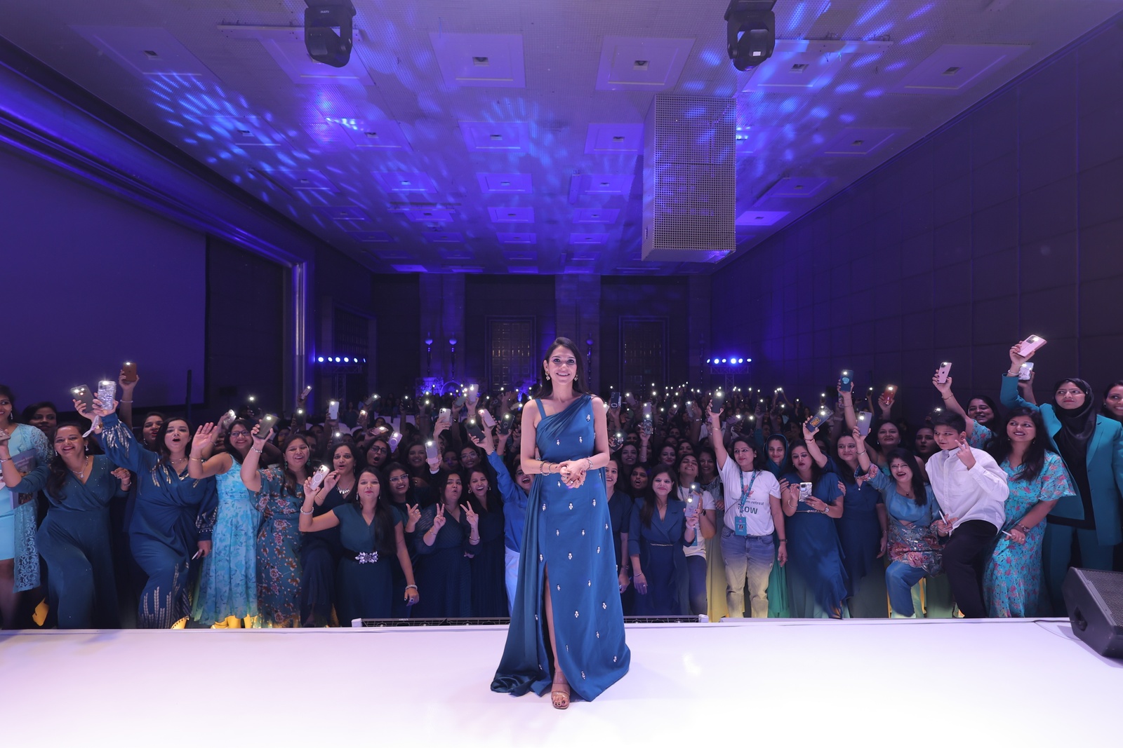 Riddhi Deorah on stage with hundreds of mothers behind her